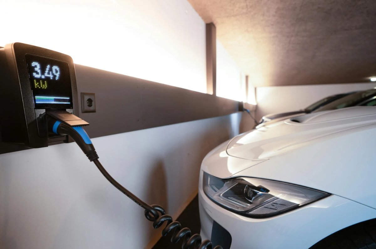 Carregador com display de potência ao lado de veículo elétrico em garagem